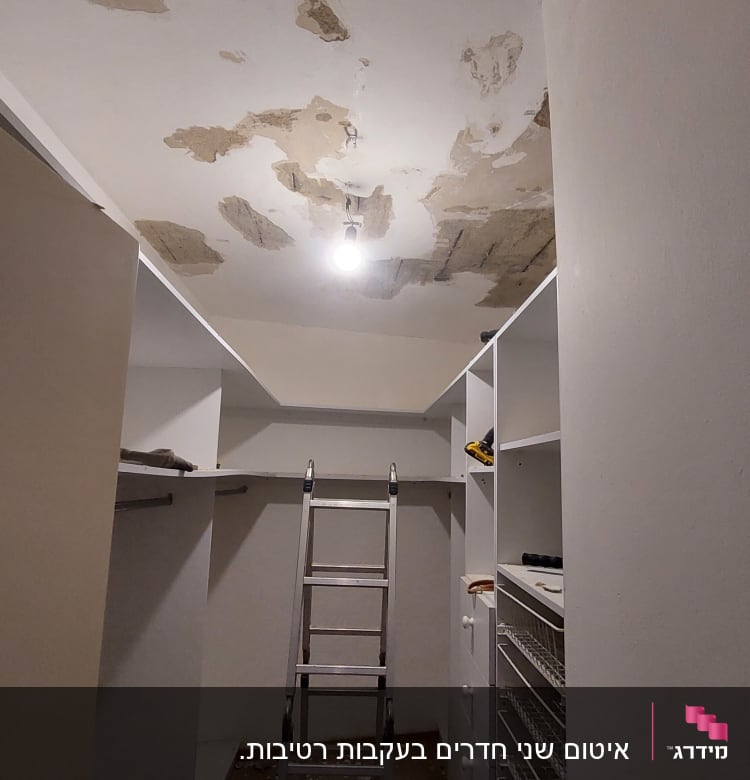 סולם מתכת מתחת לתקרה מתקלפת עם נורה חשופה